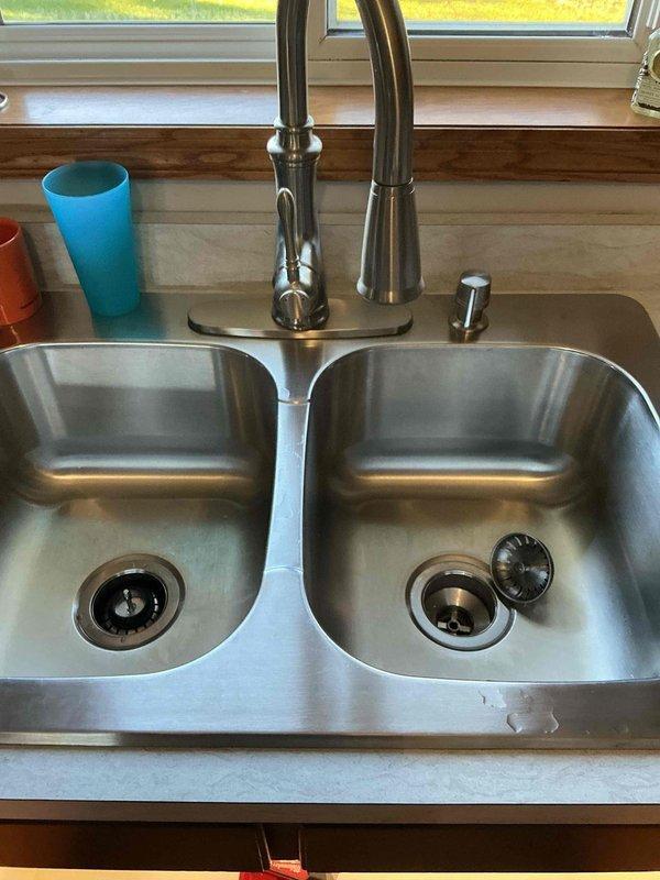 Responded to service call for kitchen sink backup. Investigation revealed drainage issues when sink and dishwasher were in use, despite clear P-trap. Successfully restored proper drainage function by augering the kitchen sink line, clearing blockage located beyond the trap assembly.