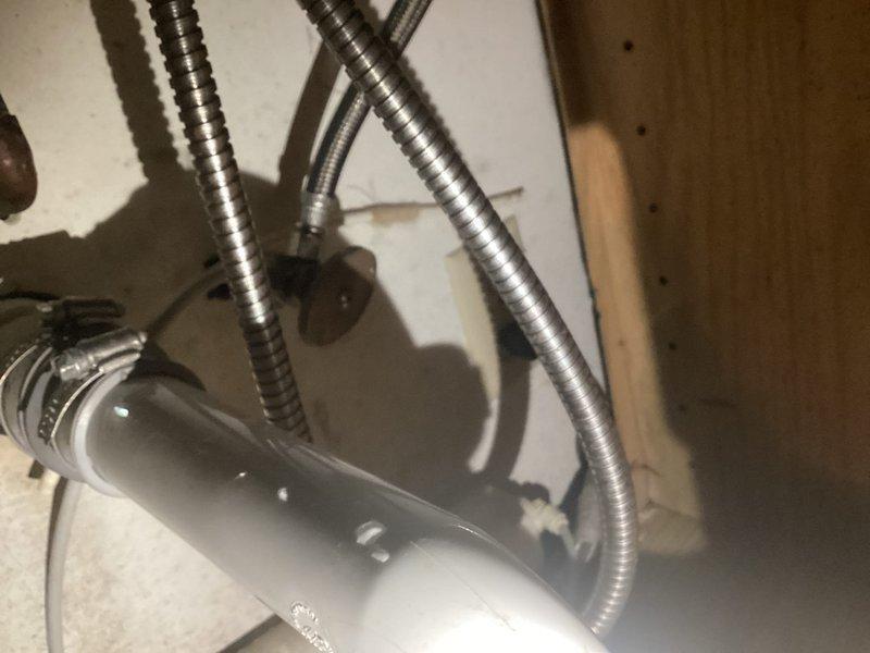 Diagnosed leak coming from single-stage RO system under kitchen sink. Found water pooling beneath the unit with visible droplets on PVC piping and staining on cabinet wall. Removed the faulty RO system including filter cartridge and disconnected associated supply lines to resolve the immediate leak issue.