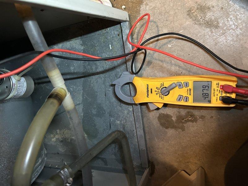 Performed diagnostic inspection on 15-20 year old natural gas forced air furnace following customer's new enrollment in Family Rewards program. Identified and cleared plugged condensate drain that was causing intermittent operation issues as water would accumulate and trigger shutdown until drained. Conducted comprehensive maintenance including heat exchanger inspection and electrical component testing with multimeter verification. Replaced aging thermostat with difficult buttons. System now operating normally with proper drainage.