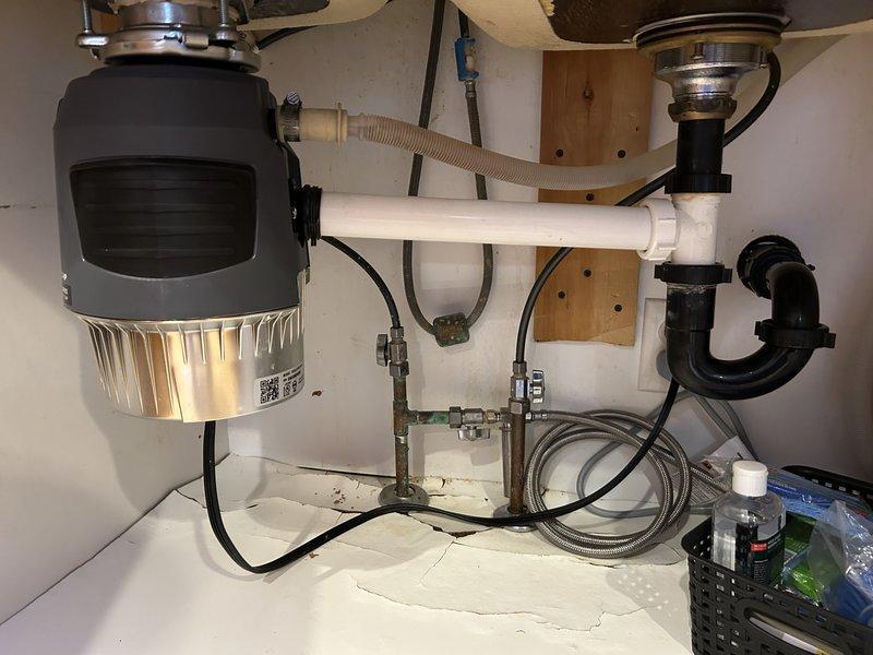 Removed unnecessary second trap that was causing garbage disposal to leak during operation. Properly replumbed disposal unit into existing plumbing system, eliminating vibration issues that were previously causing pipe disconnection. Installed direct connection with proper P-trap configuration to ensure stable, leak-free operation.