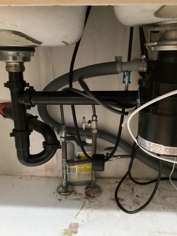 Shakopee, MN - Assessed customer's under-sink plumbing for installation of reverse osmosis drinking water system. Determined that existing drain pipe configuration had insufficient space for the required drain saddle installation, potentially requiring dishwasher line adaptation. Customer declined to proceed with installation after receiving price quote. Documented current plumbing setup with photos showing P-trap configuration, garbage disposal unit, and existing connections.