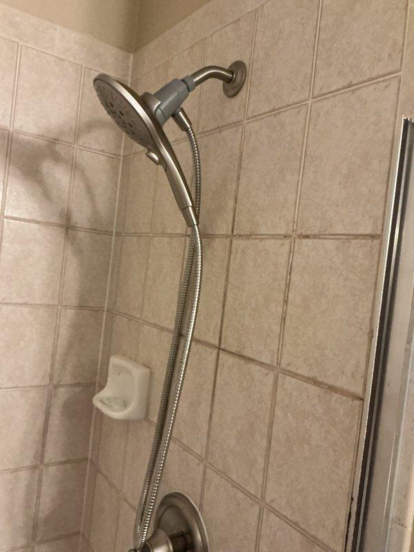 Completed shower valve replacement in bathroom. Removed old Delta cartridge that customer was unable to extract and installed new Moen shower valve with matching trim kit. Verified proper operation of new handheld showerhead with flexible hose mounted on adjustable bracket. System now functioning correctly with no leaks observed.