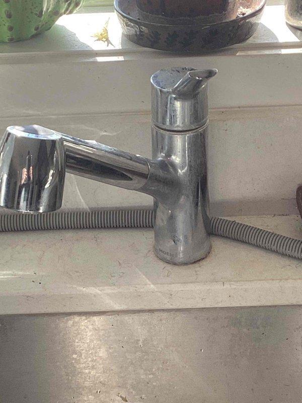 Diagnosed kitchen sink faucet leak originating from worn cartridge. Conducted inspection of chrome faucet with pull-out spray component and identified internal cartridge failure as source of water leakage. Provided customer with options for cartridge replacement versus complete faucet replacement.
