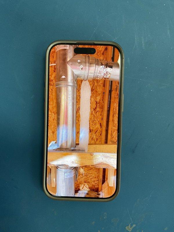 Responded to a service call for water leakage from a garage heater connector located in the attic. Identified the issue as an improperly seated flue vent pipe at one of the fittings at the hip junction. Reinserted the Class B vent pipe securely and installed new screws to ensure proper connection and prevent further leakage.