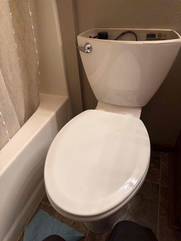 Responded to service call for toilet tank leakage. Diagnosed issue as loose tank bolts causing water to escape from tank. Tightened bolts to secure tank, then tested by allowing water to fill and monitoring for 10 minutes, followed by multiple flush tests. No further leaks observed after repair.