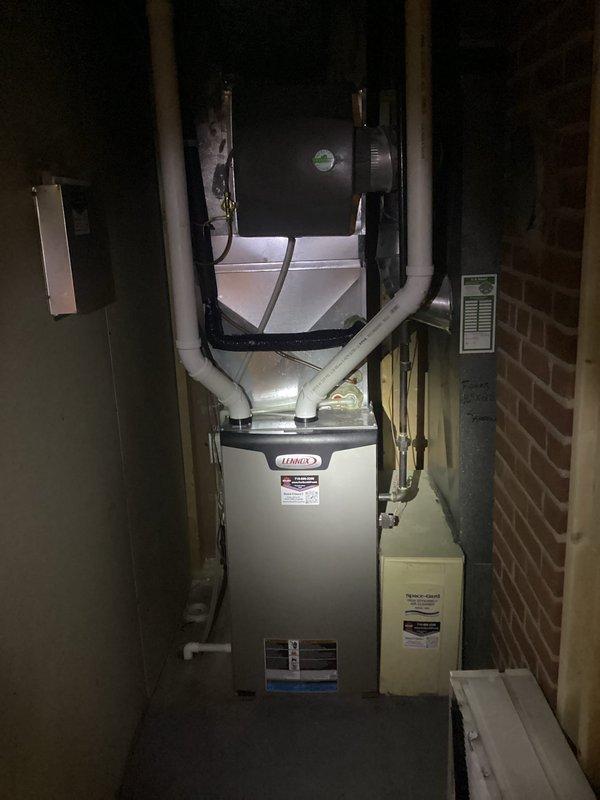 Responded to service call for Lennox gas furnace (3 years old) making humming noise. Customer had already resolved initial rattling by adjusting humidifier damper from summer to winter position. Discovered water leakage in lower cabinet due to incorrect furnace pitch; removed front pads and re-pitched unit to proper orientation. Noted humidifier functioning improperly with clogged pad; recommended seasonal damper operation, but customer declined humidifier repair.