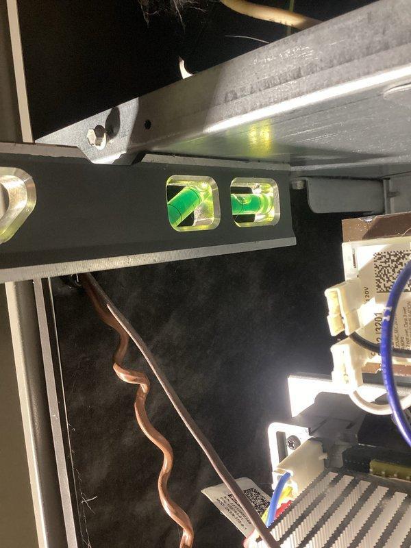 Responded to service call for Lennox gas furnace (3 years old) making humming noise. Customer had already resolved initial rattling by adjusting humidifier damper from summer to winter position. Discovered water leakage in lower cabinet due to incorrect furnace pitch; removed front pads and re-pitched unit to proper orientation. Noted humidifier functioning improperly with clogged pad; recommended seasonal damper operation, but customer declined humidifier repair.