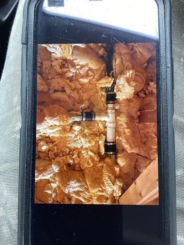 Responded to a water leak call at a residential property where an ABS 90 fitting was improperly glued and leaking from the vent boot in the attic. Accessed the confined space, removed affected spray foam insulation to expose the damaged plumbing, and replaced two 90-degree fittings with 2" PVC components properly tied into the existing ABS system. Leak was successfully repaired and system tested to confirm resolution.