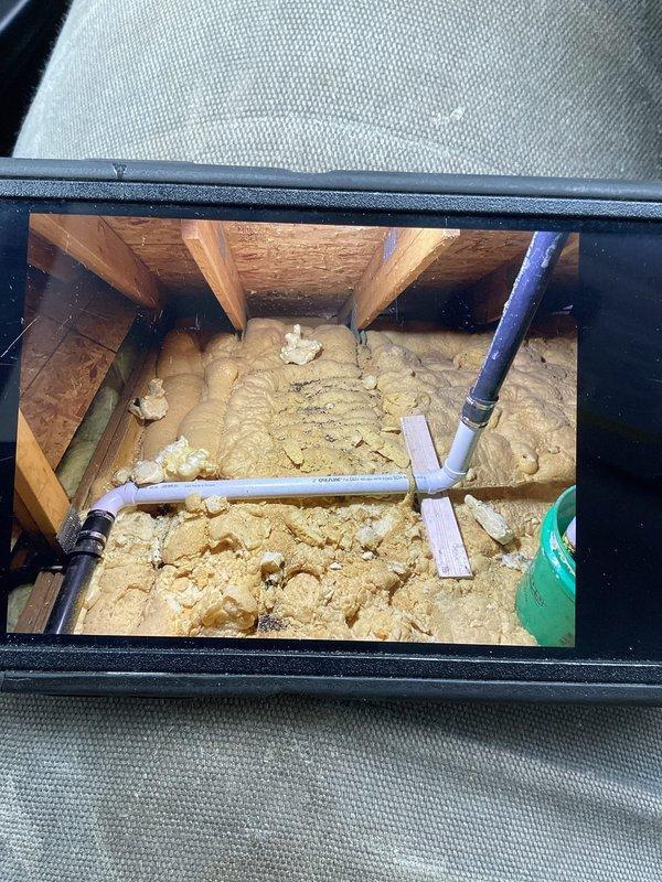 Responded to a water leak call at a residential property where an ABS 90 fitting was improperly glued and leaking from the vent boot in the attic. Accessed the confined space, removed affected spray foam insulation to expose the damaged plumbing, and replaced two 90-degree fittings with 2" PVC components properly tied into the existing ABS system. Leak was successfully repaired and system tested to confirm resolution.