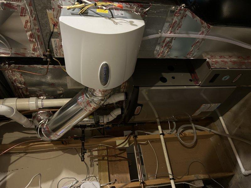 Responded to service call for humidifier valve replacement. Previous technician was unable to complete the installation of a 1/4" line for the residential humidifier due to leaking valve and lack of proper fittings. Successfully replaced the failed humidifier valve on the HVAC system mounted to the furnace ductwork in the utility area, resolving the leak issue and ensuring proper operation.