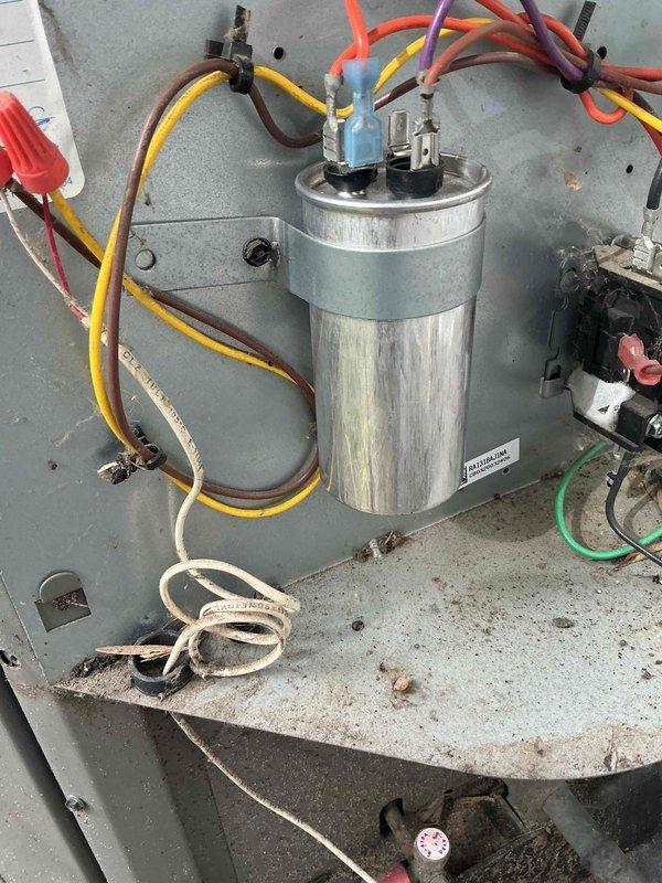 Responded to no-cooling complaint on 5-year-old Rheem AC system. Diagnosed failed capacitor (visibly bubbled on top) which prevented fan motor operation. Replaced capacitor, restoring proper system function and cooling. Customer reported neighborhood power fluctuations likely contributed to component failure.