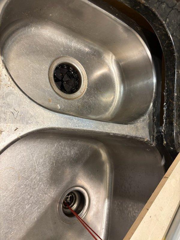 Responded to service call for undermount kitchen sink detachment from granite countertop. Inspected mounting hardware which showed significant corrosion on the L-bracket and threaded components. Re-secured double-basin stainless steel sink to countertop using replacement clamps and properly tightened mounting hardware. Completed installation of kitchen faucet.