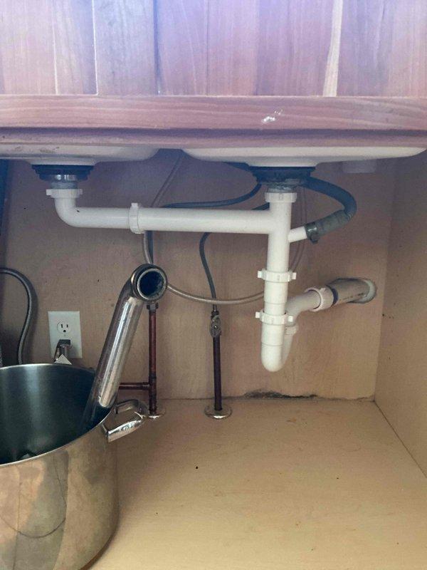 Replaced corroded cast iron waste lines under kitchen sink with new PVC piping to resolve active leakage. Installed new kitchen faucet fixture as part of complete plumbing update. All connections verified secure with no further signs of water damage or leakage.