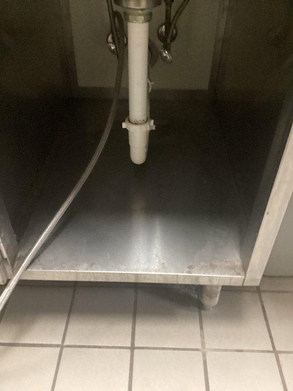 Responded to recurring main drain backup issue in commercial kitchen. Diagnosed sugar buildup causing floor drain clog, then utilized drain cable to clear the line and restore proper drainage function. Inspected associated under-sink plumbing to verify complete system functionality.