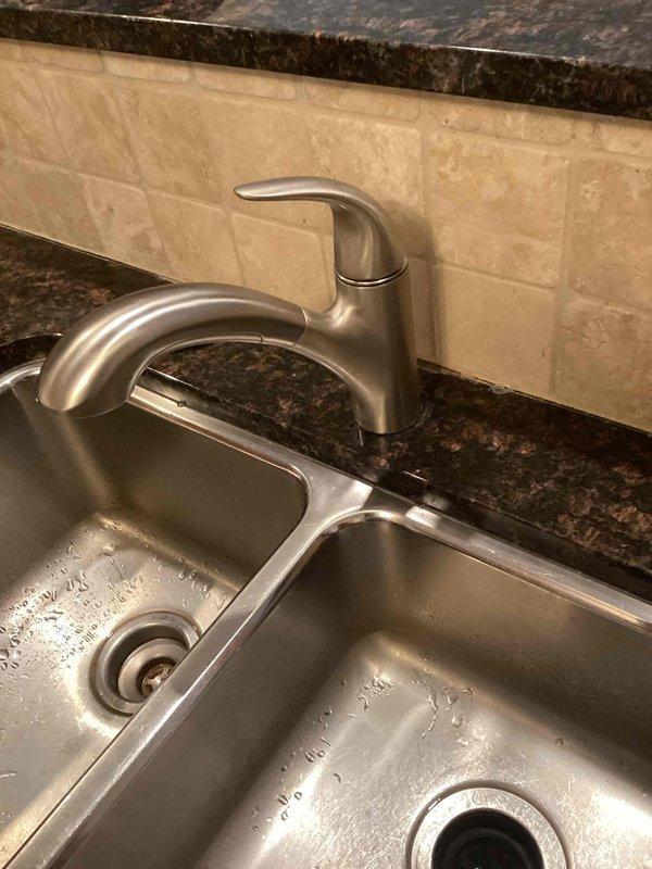 Responded to service call for a loose Moen kitchen faucet, approximately two years old. Upon inspection of the double-basin stainless steel sink with brushed nickel faucet, identified issue with loose handle. Tightened set screw to restore proper functionality and stability to the faucet handle.
