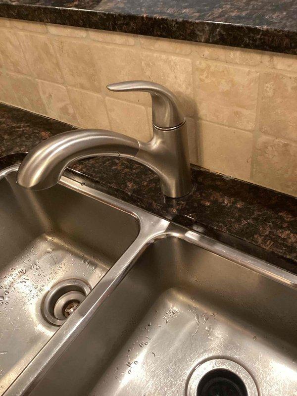 Responded to service call for a loose Moen kitchen faucet, approximately two years old. Upon inspection of the double-basin stainless steel sink with brushed nickel faucet, identified issue with loose handle. Tightened set screw to restore proper functionality and stability to the faucet handle.