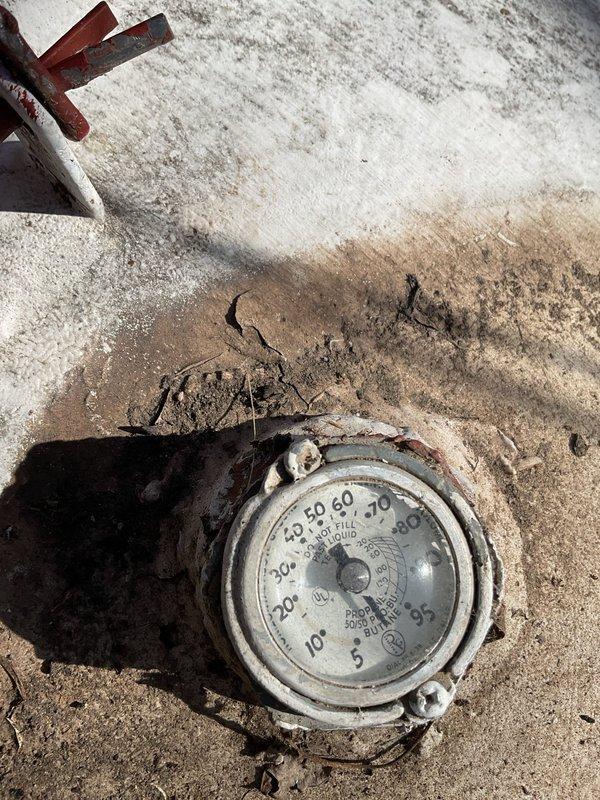 Responded to no heat call and found LP furnace had run out of fuel, resulting in severe soot buildup throughout the system including flue pipe and secondary garage heater. Upon inspection, discovered heat exchanger leak with sooted condensate visible on floor beneath unit. Documented conditions with photos of gauge and exterior PVC vent terminations, advised of necessary replacement, and scheduled follow-up consultation.