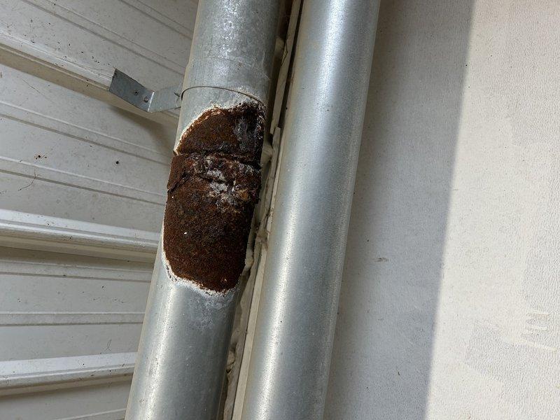 Diagnosed unit failure in barn heater due to severe heat exchanger deterioration. Observed significant corrosion with multiple holes in the header pipe and cracking eyelets causing flame extinguishment when blower activates. Performed temperature diagnostics and determined replacement of the hanging heater is required due to unsafe operating condition.