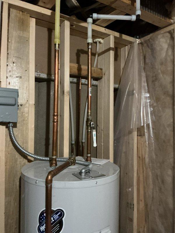 Completed annual plumbing inspection revealing two non-functioning fixtures: kitchen sink spigot and water line to refrigerator. Documented existing water heater installation with copper and PVC connections in utility area, and inspected wall-mounted Water Factory Systems filtration unit with three filter cartridges (blue, green, and yellow tops) that appears to be in working condition.