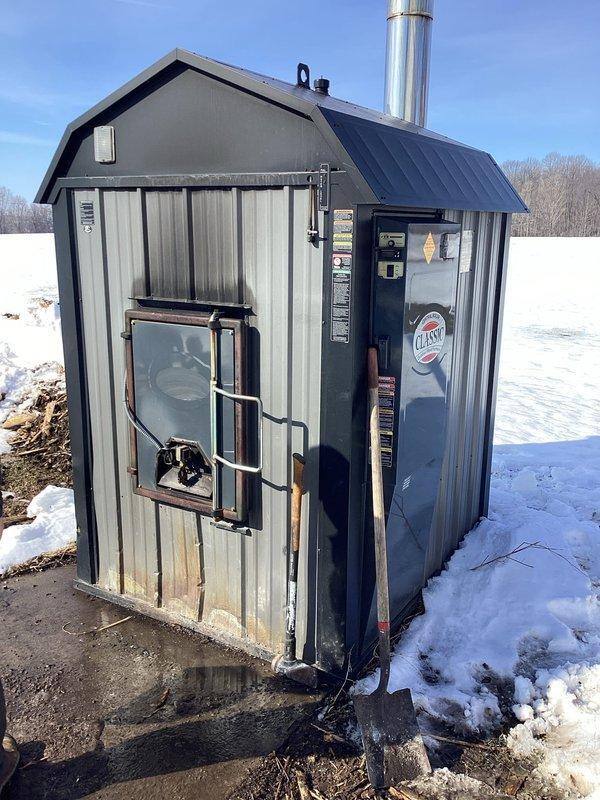 Performed comprehensive outdoor wood boiler tune-up service, identifying loose door rope, lubricating door solenoid and hinges, and noting chimney beginning to plug. Inspected indoor components including coils (found evaporator beginning to soil), heat exchanger (no compromises), and verified proper water levels and pump operation. Secondary furnace inspection revealed cracked collector box and noisy inducer motor; recommended follow-up for replacement/repair options.