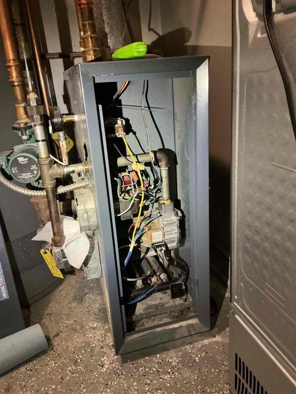 # Service Report: Gas Leak at Boiler

Responded to gas odor complaint following recent thermal couple replacement by another contractor. Upon inspection, discovered active gas leak at boiler gas valve tubing connection. Found hardened putty compound around fitting with gas escaping through small opening in sealant. Immediately shut off gas supply line and boiler system to eliminate safety hazard. Documented conditions with photographs showing VR8200A gas valve assembly and mechanical room configuration. System left in safe, de-energized state pending proper repair of leaking gas valve connection.