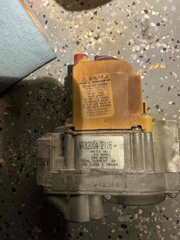 # Service Report: Gas Leak at Boiler

Responded to gas odor complaint following recent thermal couple replacement by another contractor. Upon inspection, discovered active gas leak at boiler gas valve tubing connection. Found hardened putty compound around fitting with gas escaping through small opening in sealant. Immediately shut off gas supply line and boiler system to eliminate safety hazard. Documented conditions with photographs showing VR8200A gas valve assembly and mechanical room configuration. System left in safe, de-energized state pending proper repair of leaking gas valve connection.