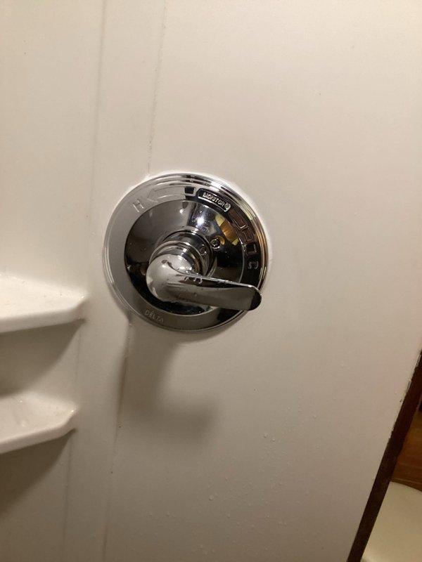 Completed installation of partially installed Delta shower control valve in basement shower. The valve body had been previously set in place but required final assembly and finishing work. Installed trim components including chrome escutcheon plate and single-handle lever control with hot/cold indicators. Verified proper valve operation and water flow control. All connections secured and fixture mounted flush to wall surface for clean, functional appearance.