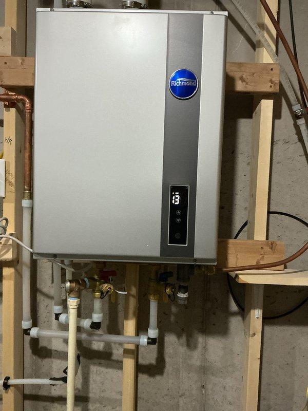 Performed diagnostic assessment on Richmond tankless water heater that was not maintaining adequate flow capacity for multiple fixtures. Observed unit was only able to service one faucet at a time, suggesting scale buildup in heat exchanger. Discussed descaling options with customer, who declined professional service and opted to purchase their own descaling kit. Visual inspection showed proper installation with all connections intact and no visible leaks.