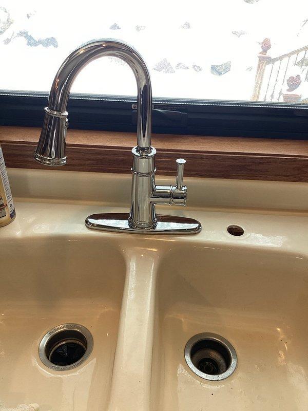 Replaced customer-supplied faucets in two locations: installed a modern chrome single-lever faucet in the bathroom where cold water flow was compromised, and replaced an aging kitchen faucet with a new high-arch pull-down sprayer model. Both installations were completed successfully with proper function verified.