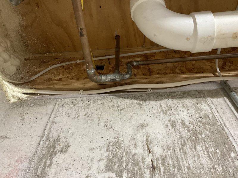 Conducted comprehensive inspection of residential water treatment system, including multiple filtration tanks (two blue cylindrical, one gray/beige, and one black brine tank) with digital control panels and associated PVC plumbing. Examined drainage components, including main white PVC drain pipe with elbow joint and connected metallic piping, documenting current condition with photos for reference.