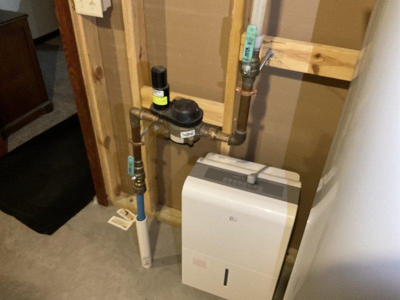 Performed comprehensive plumbing inspection of residential property, examining both exposed PVC and copper pipe installations. Inspected wall-mounted plumbing components, water meter/regulator valve, and connection points for proper sealing and secure mounting, with particular attention to the dehumidifier/HVAC system integration with the home's plumbing infrastructure.