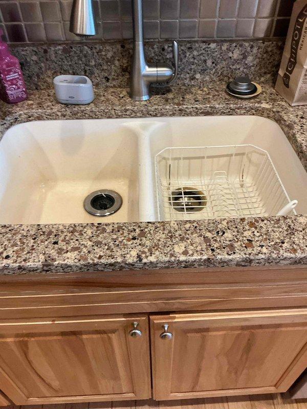 Responded to service call for kitchen sink clogged drain causing water to back up under sink when garbage disposal activated. Diagnosed significant grease buildup in the drain system. Successfully cleared blockage using drain snake, restoring proper drainage and eliminating backup issues.
